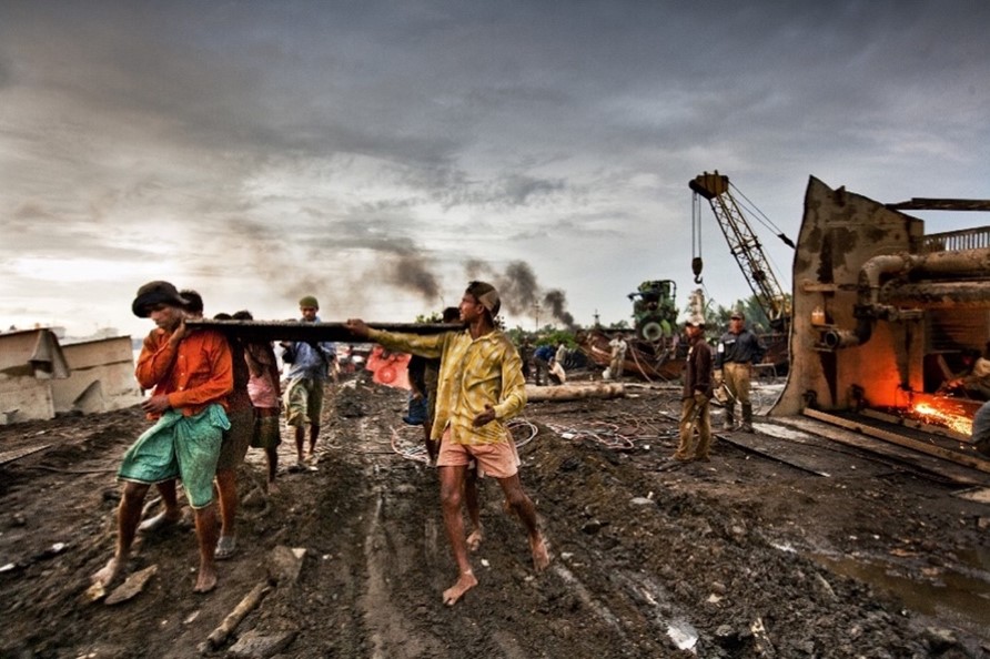 Shipbreaking Workers Carrying Metal Sheet, 2008, by Shahidul Alam, Courtesy of the artist.