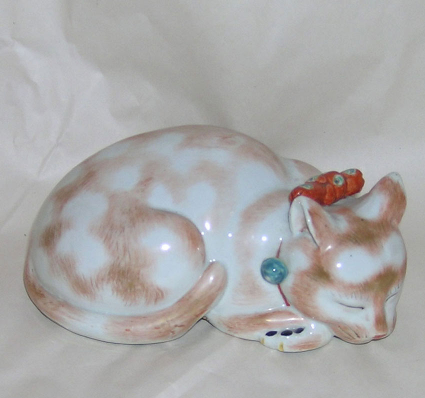 A porcelain model of a recumbent sleeping cat